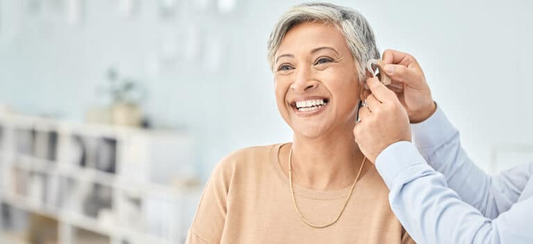 Woman getting fitted for hearing aids to help manage her hearing and brain health